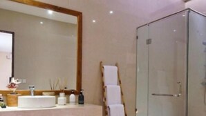 A bathroom with a large mirror, a sink, and a glass shower enclosure. - Soleil Suites Petitenget By the jero 18 (Keroboken Kelod)