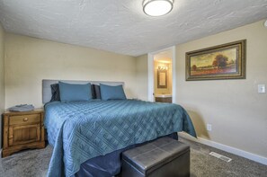 A bedroom with a bed, nightstand, bench, and a painting on the wall. - Mighty Mobile (Palmer Lake)