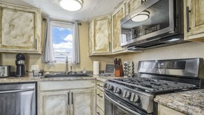 Una cocina con electrodomésticos de acero inoxidable, un ventanal y vista al cielo.
