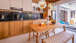 A modern kitchen with wooden cabinets, a built-in stove, and pendant lighting. -  Villa Sorano Canggu by Nagisa Bali (Kerobokan)