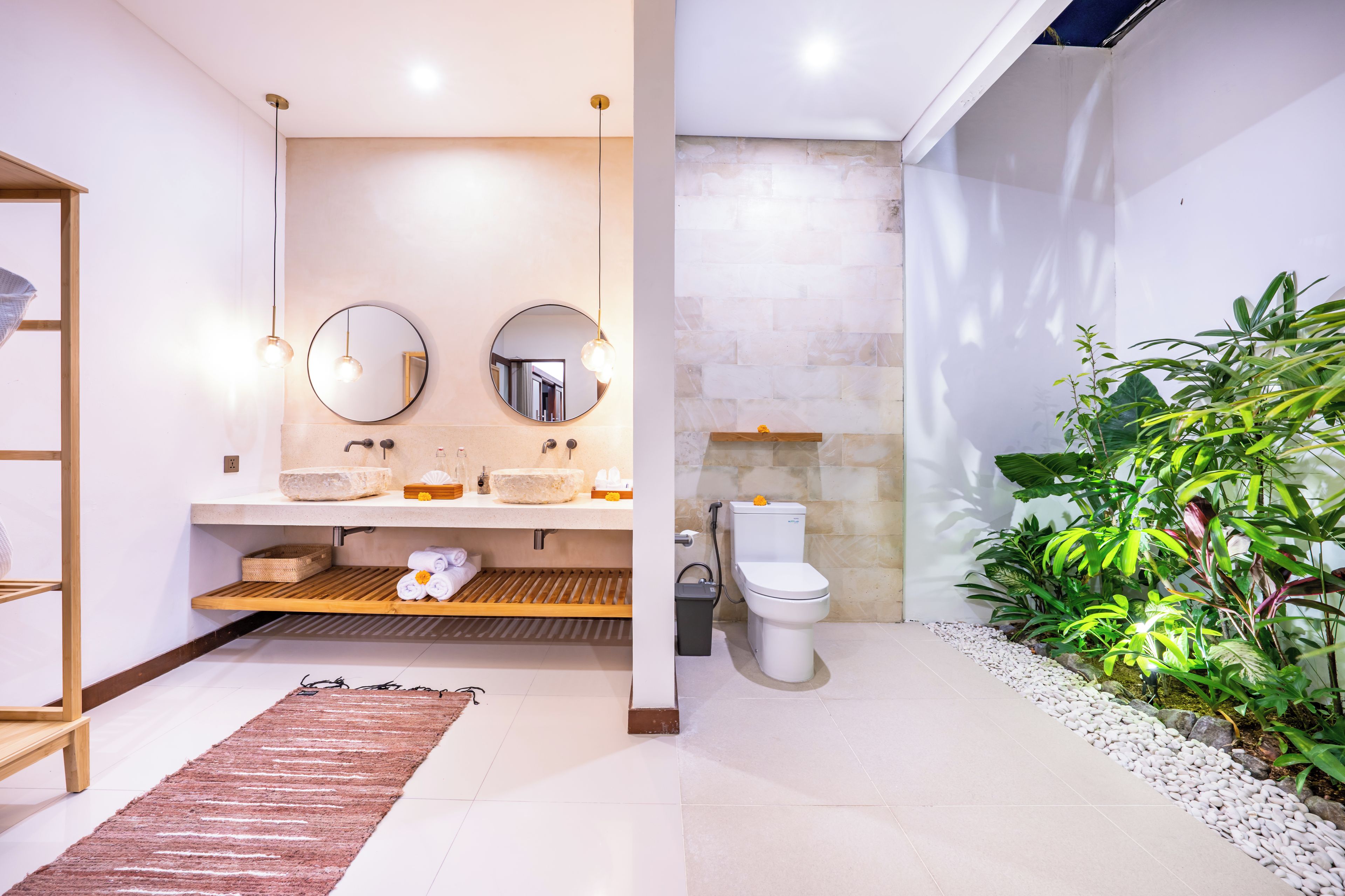 Une salle de bain moderne avec un lavabo en pierre, deux miroirs ronds et des toilettes.