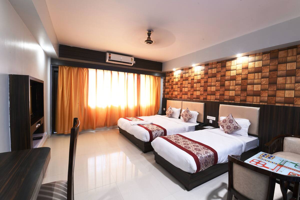 Ein Hotelzimmer mit zwei Betten, einem Fernseher, einem Esstisch und einem Gesellschaftsspiel.