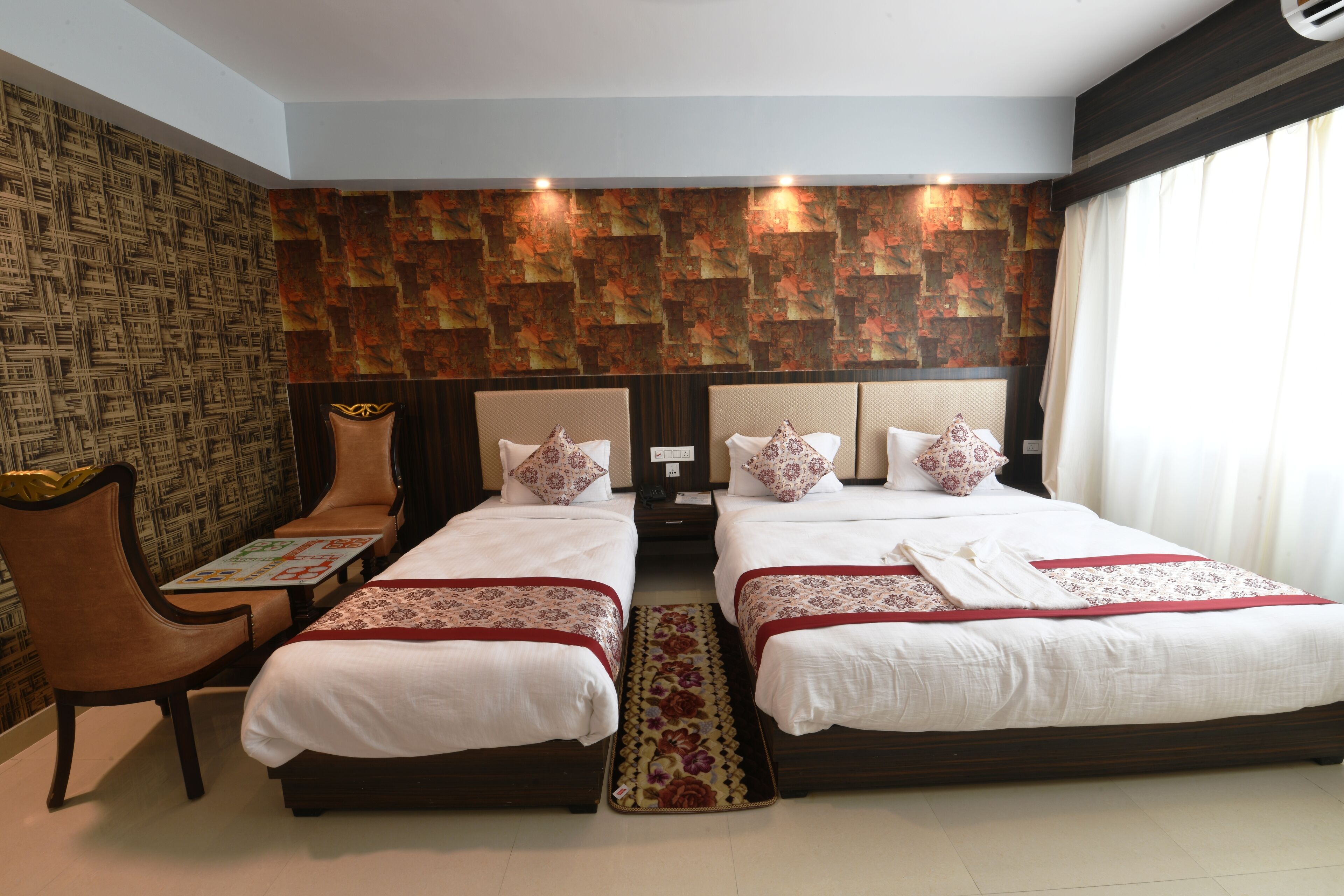 A hotel room with two beds, a small table, and a chair.