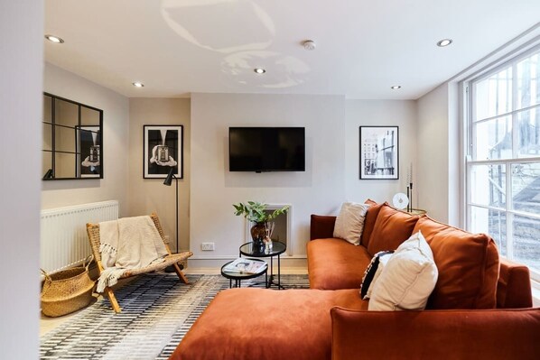 A modern living room with a sofa, a chair, a TV, and a large window.