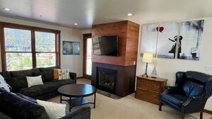 A living room with a fireplace, a television, a sofa, a chair, and a small table.