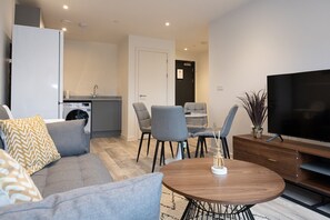 A modern living room with a grey sofa, a wooden coffee table, and a flat-screen TV.