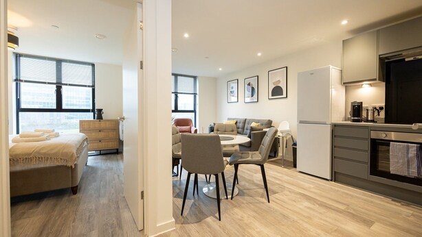 Un appartement moderne comprenant un coin repas, une cuisine et une chambre dotée d’une grande fenêtre.