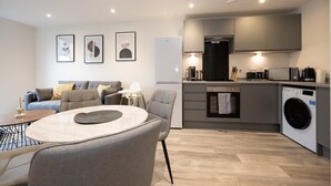 Un appartement moderne comprenant un espace de vie, une kitchenette et un coin buanderie compact.