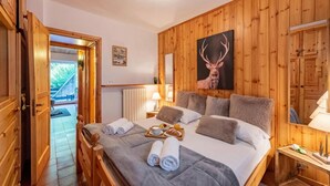 A wooden-paneled room with a bed, towels, a breakfast tray, and a deer antler painting. - Chaberton Romantic Retreat Ski In Ski Out, Claviere, Italy (Claviere)