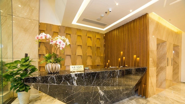 A reception desk with a marble counter, a potted plant, and a sign that reads "Lé Tân Reception". - Sunset Sea Hotel (Da Nang)