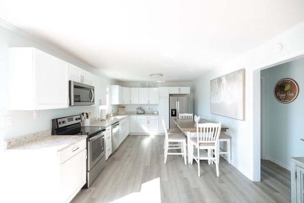 A modern kitchen with white cabinetry, stainless steel appliances, and a breakfast bar.