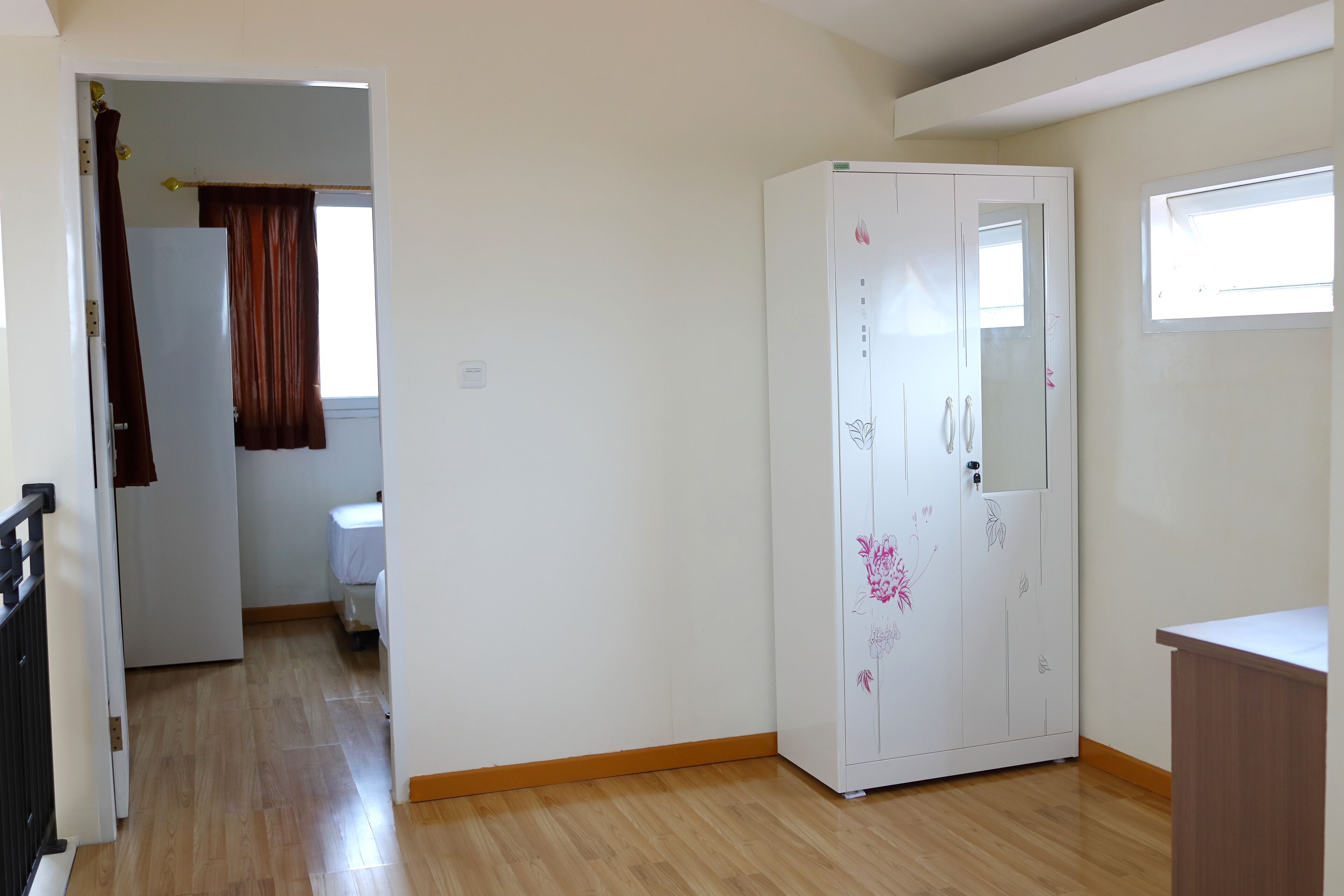 A room with a wardrobe, a bed, and a window.