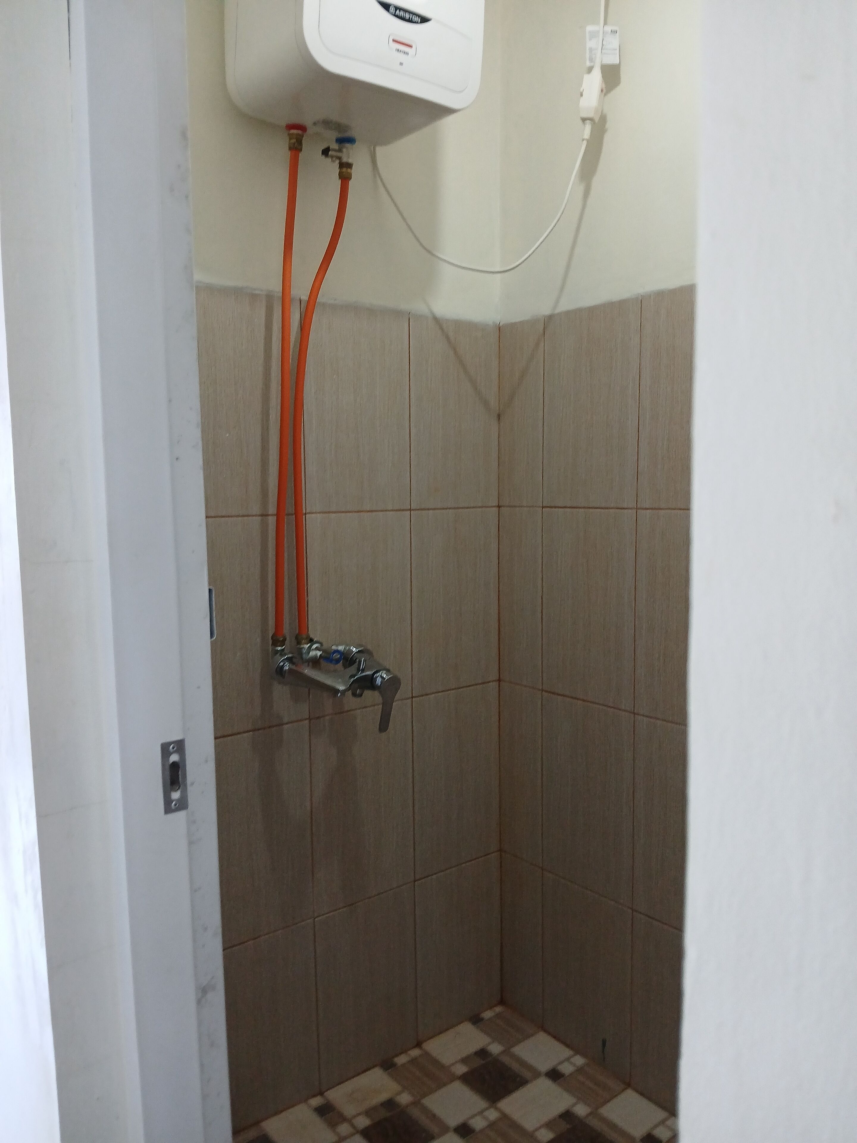 A bathroom with a shower, tiled walls, and a checkered floor.