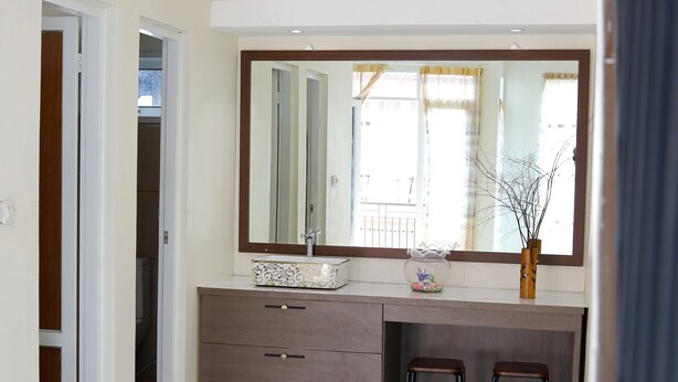 A bathroom with a marble floor, a vanity with a mirror, two stools, and a small window. - Bungo Bed Breakfast Workation (Bukittinggi)