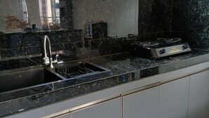 A kitchen with a black countertop, a sink, and a stove. - Bungo Bed Breakfast Workation (Bukittinggi)