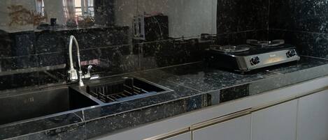 Una cocina con encimera negra, un fregadero y una estufa.