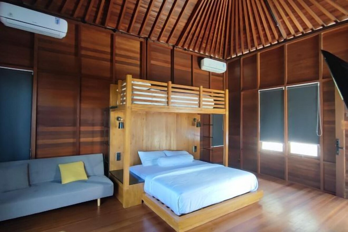 A wooden cabin room with a bunk bed, a sofa, and a shower area.