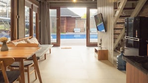 A modern kitchen with a large water dispenser, a built-in TV, and a dining area with a bench and table. - SMARANALA  (Nusa Dua)