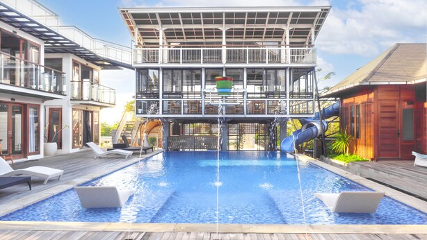A modern pool area with a multi-level structure, lounge chairs, and a water slide. - SMARANALA  (Nusa Dua)