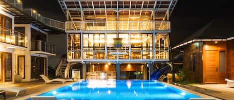 Una piscina al aire libre, sillones reclinables de piscina
