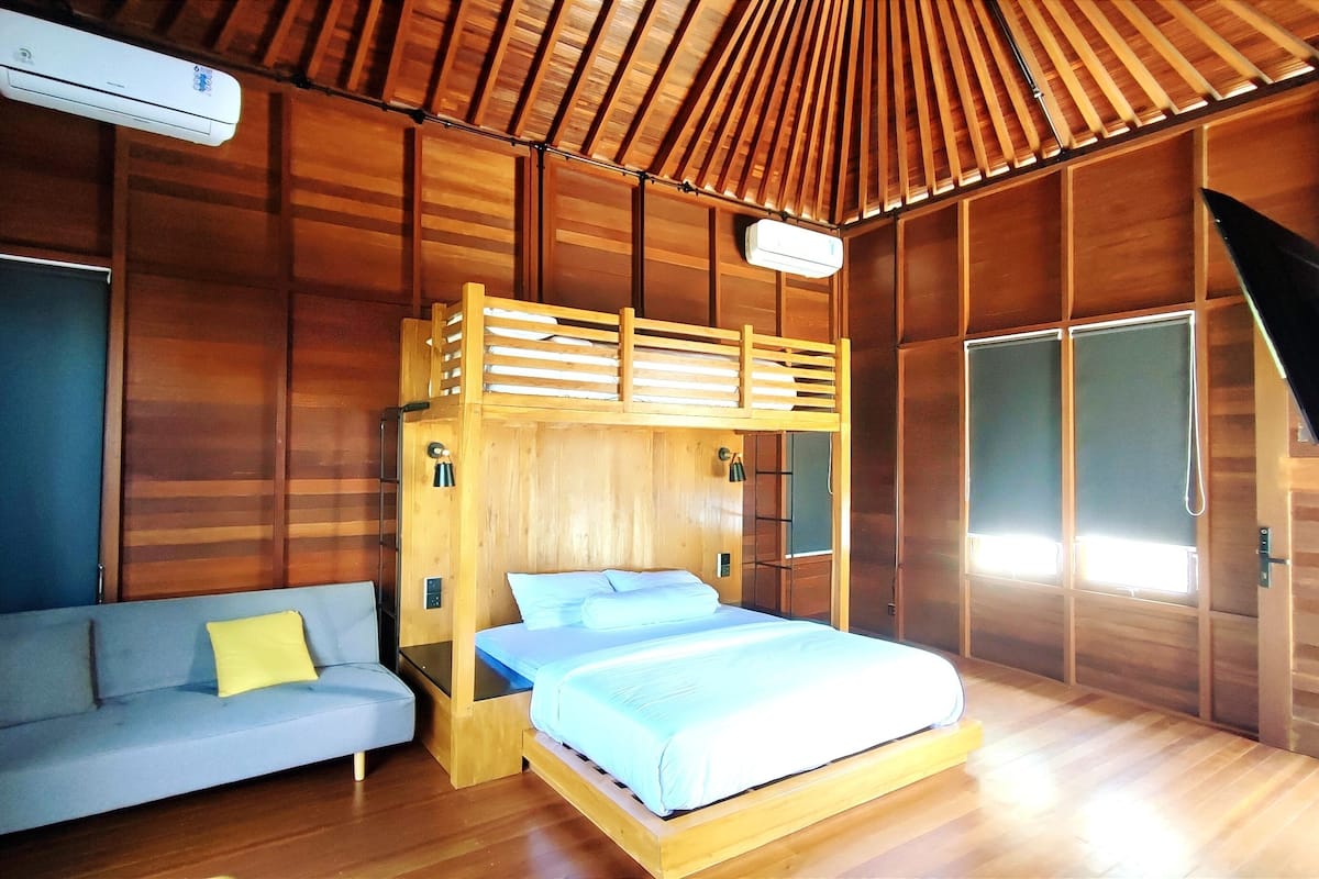 A room with a bunk bed, a sofa, and a desk.