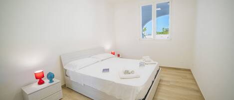 Un dormitorio minimalista con una cama, una mesita de noche y una ventana con vistas.