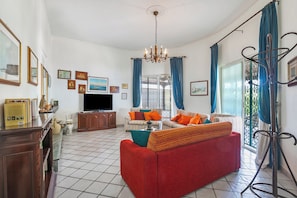A living room with a sofa, television, and a chandelier.