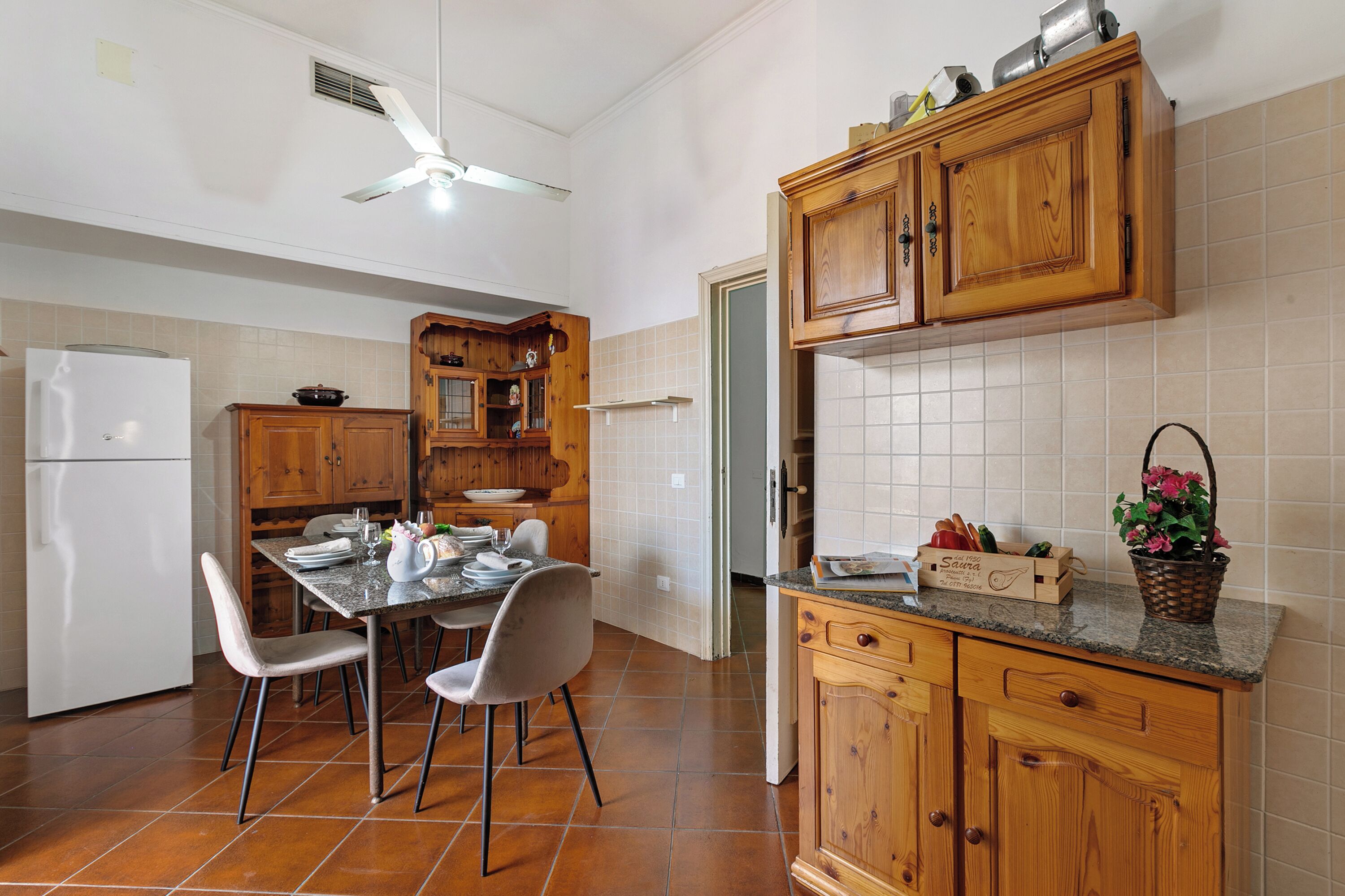 A kitchen with wooden cabinets, a white refrigerator, and a dining table with chairs.