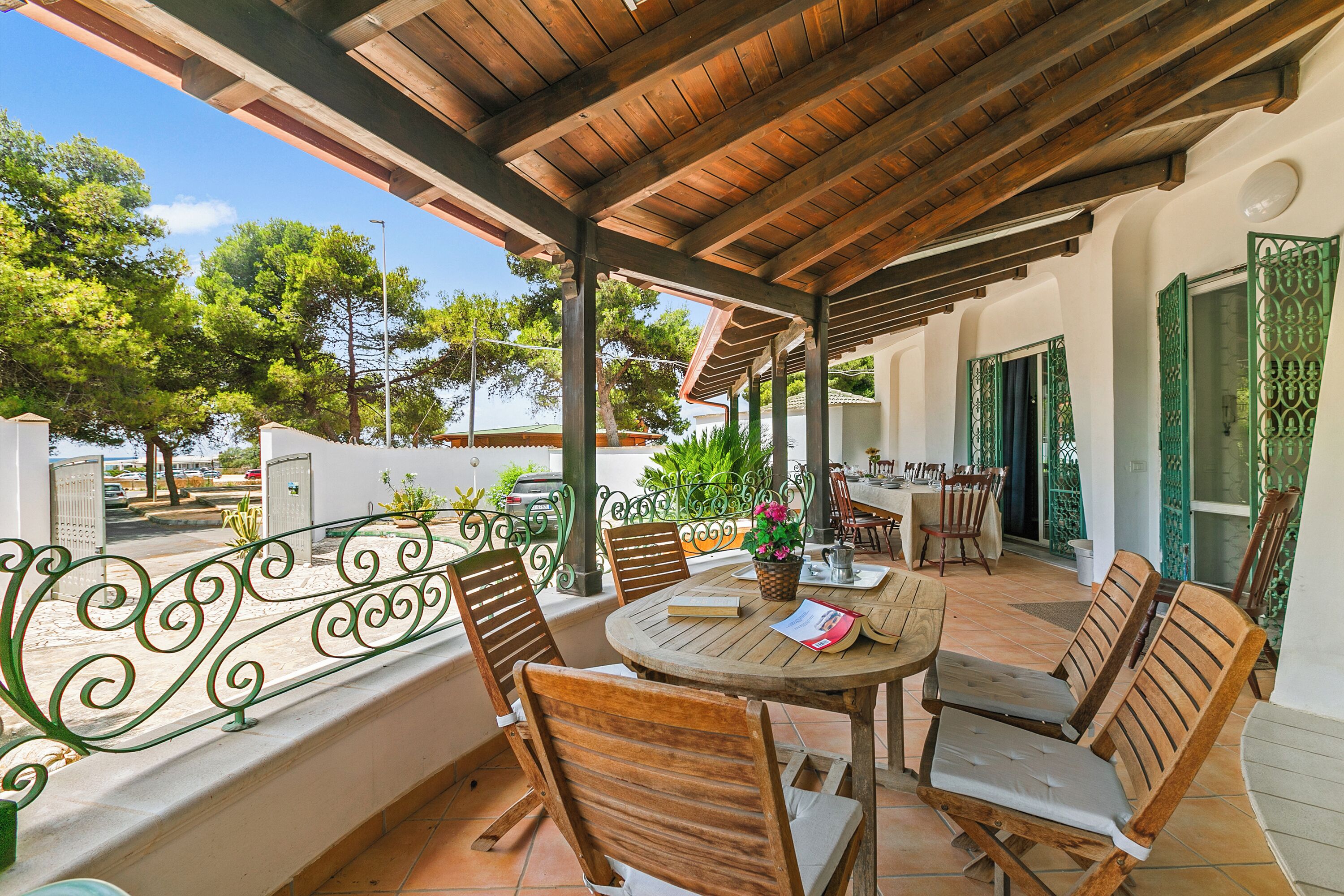 A covered outdoor patio with wooden furniture and a view of the surrounding area.