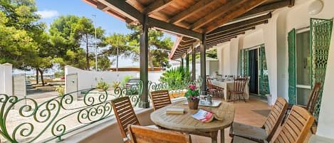 A covered outdoor patio with wooden furniture and a view of the surrounding area.