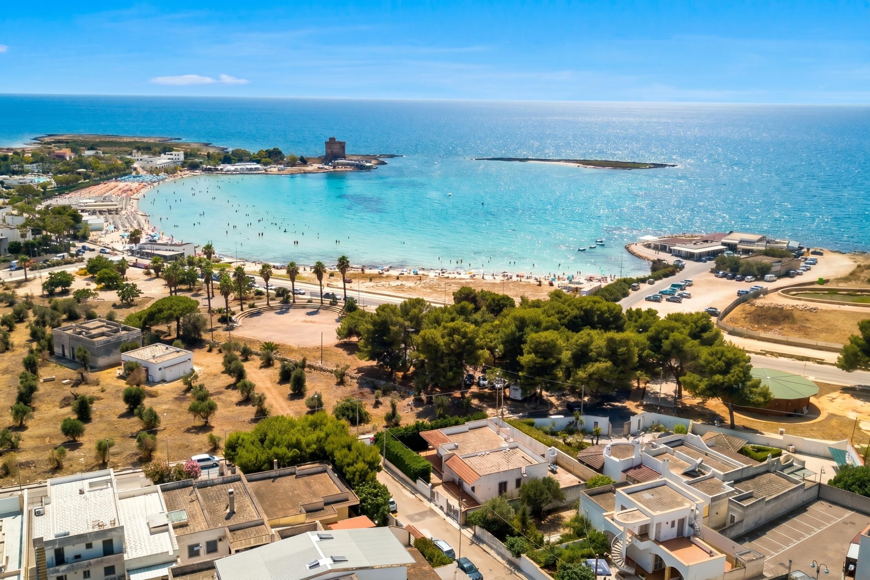A coastal town with a beach, buildings, and a clear sky.
