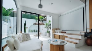 A modern living room with a large bed, a coffee table, and a staircase leading to a balcony with a view of greenery. - Mija Bhuana Agung Villa by Betterplace (Canggu)