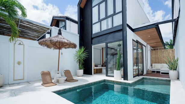 A modern pool area with a clear pool, lounge chairs, and potted plants. - Mija Bhuana Agung Villa by Betterplace (Canggu)