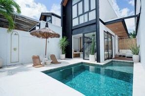 A modern pool area with a clear pool, lounge chairs, and potted plants. - Mija Bhuana Agung Villa by Betterplace (Canggu)