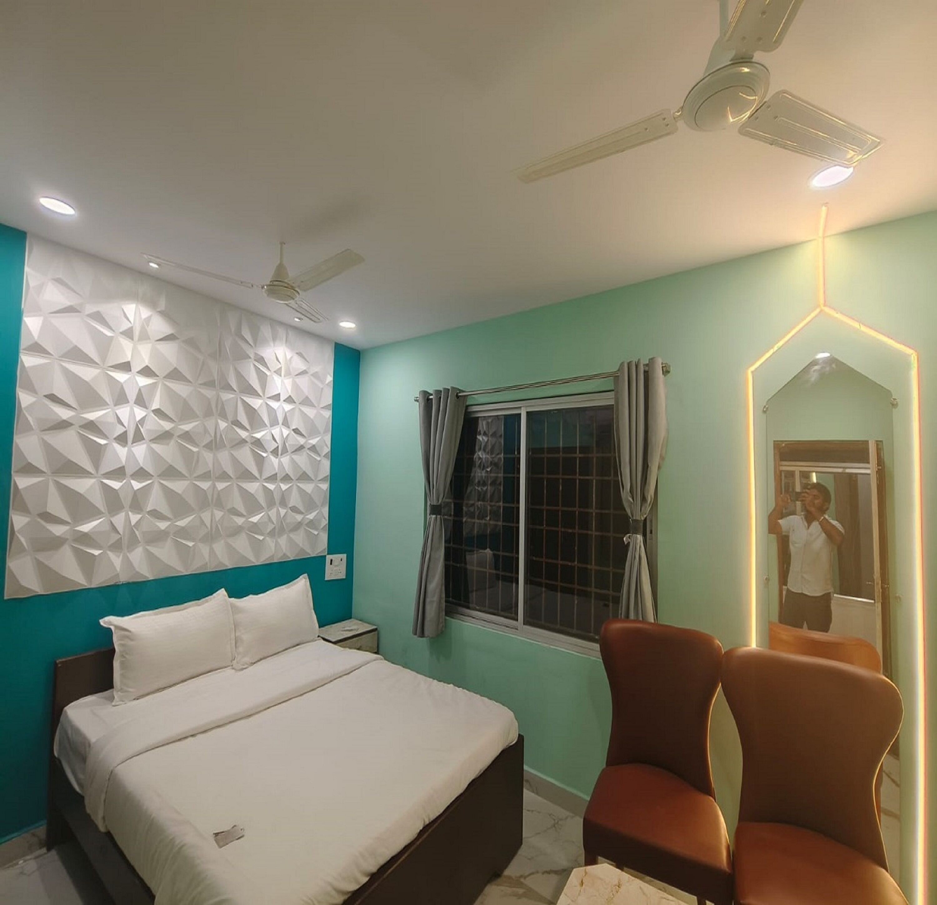 A bedroom with a bed, a nightstand, a window with curtains, a ceiling fan, and a mirror.
