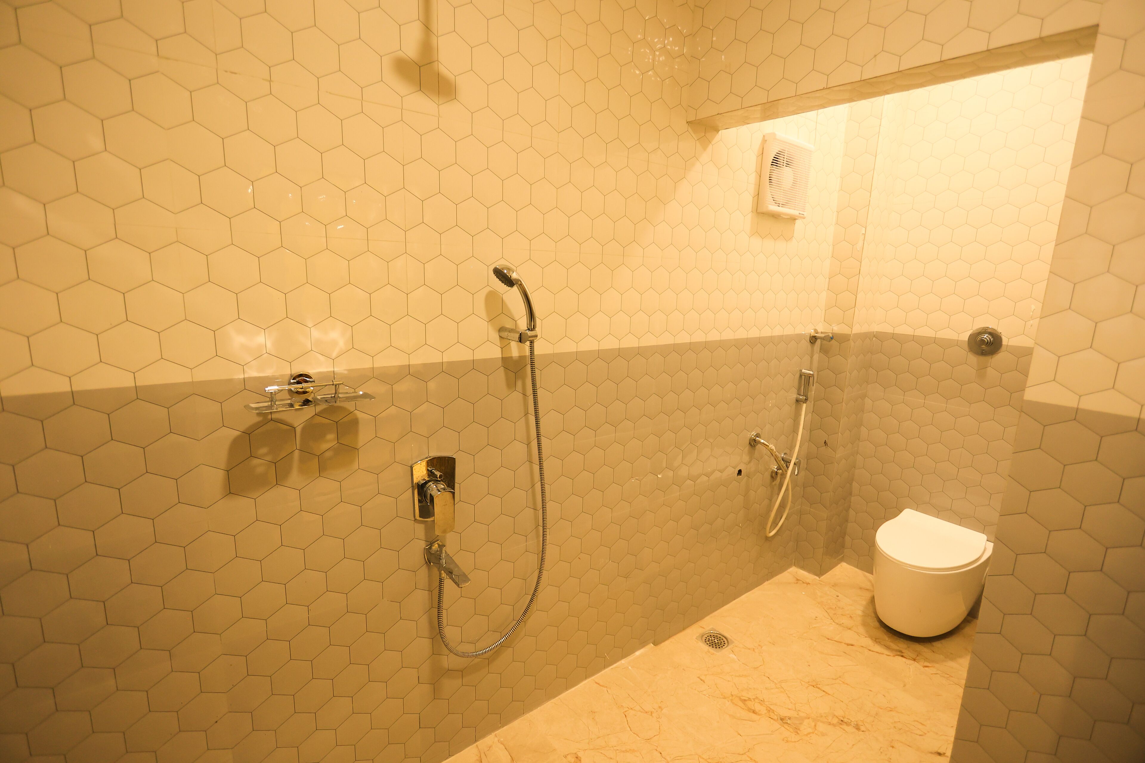 A bathroom with hexagonal tile walls, a shower, and a toilet.