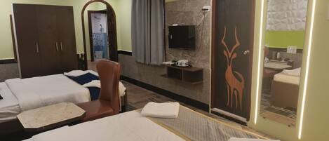 A hotel room with two beds, a TV, a mirror, and a bathroom visible through a door.