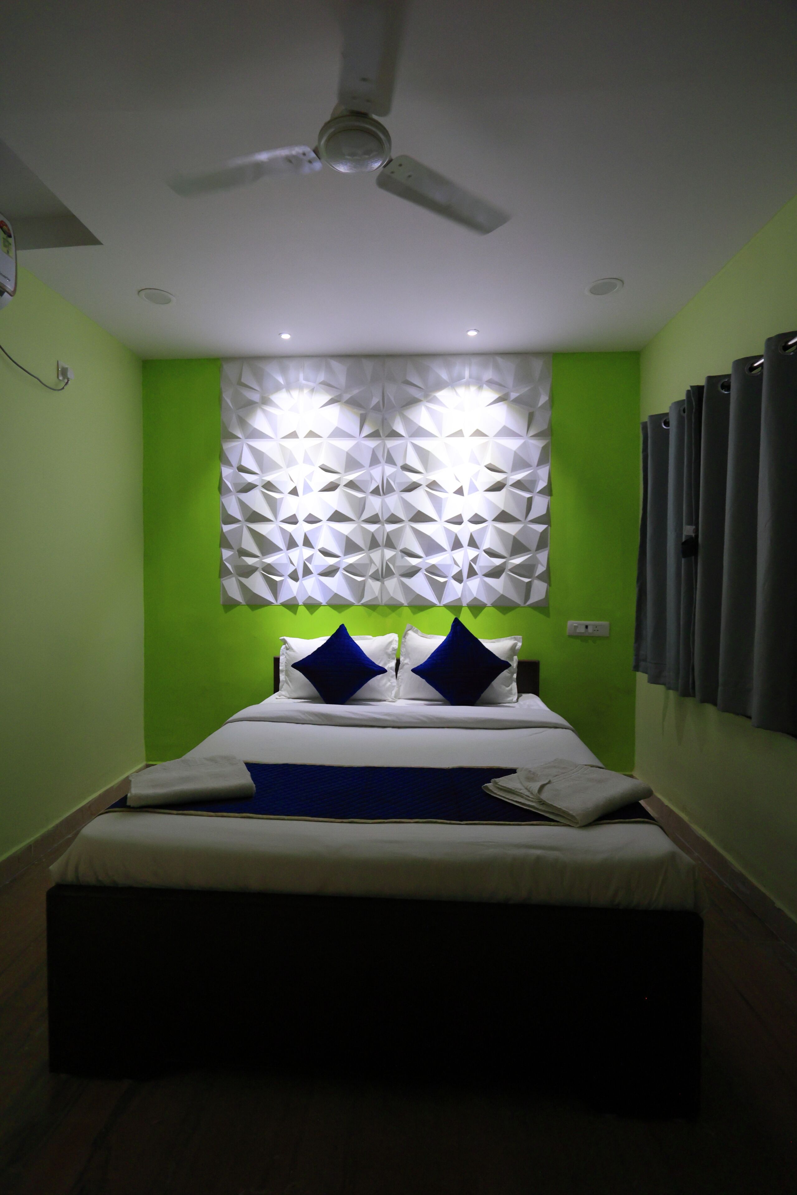 A bedroom with a bed, a ceiling fan, and a geometric wall decoration.