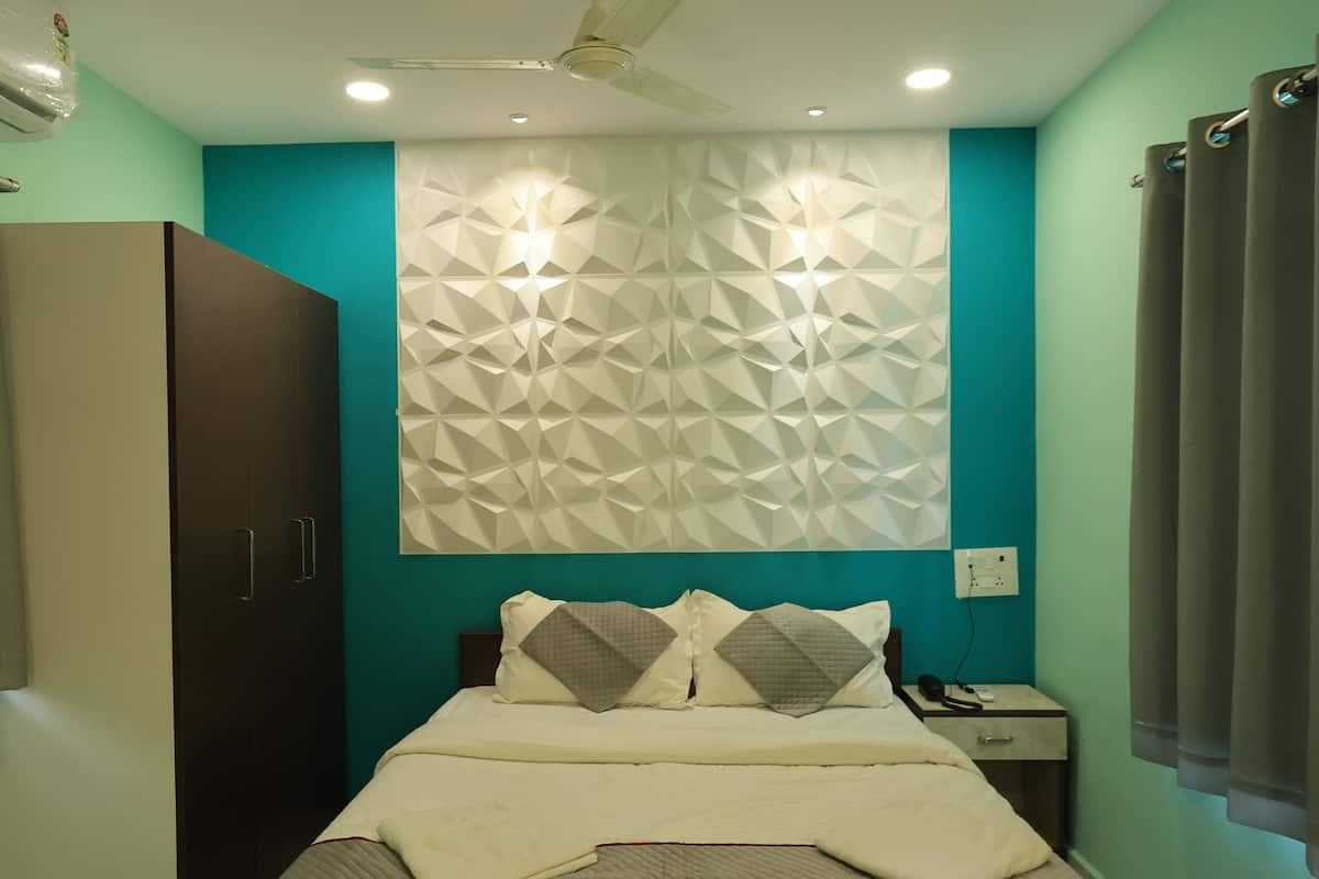 Um quarto com cama, guarda-roupa, mesa de cabeceira e ventoinha no teto.