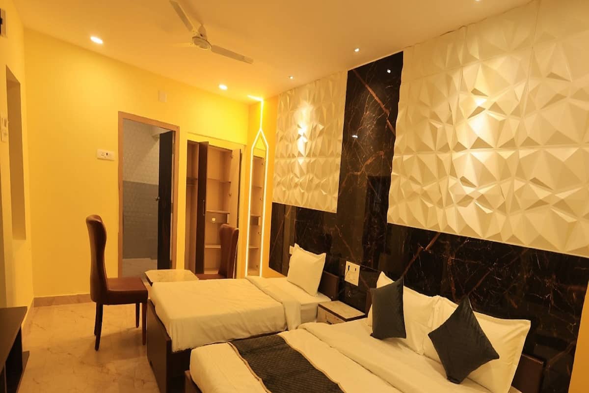 Quarto de hotel com duas camas, uma escrivaninha e uma cadeira.