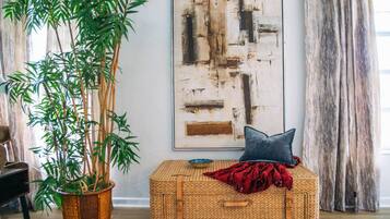Ein Zimmer mit einer großen Bambuspflanze, einem gewebten Korb, einem Kissen und einem Bild an der Wand.
