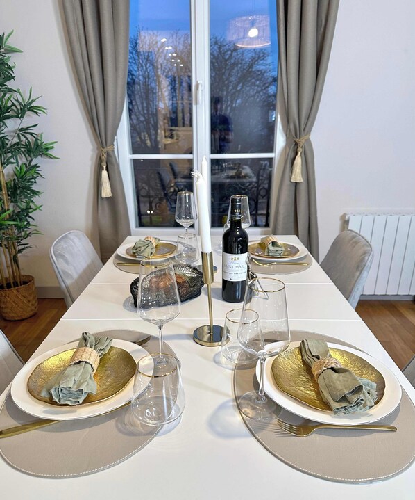 Enjoy a meal in this elegant dining room with a beautifully set table, a large window, and a potted plant.