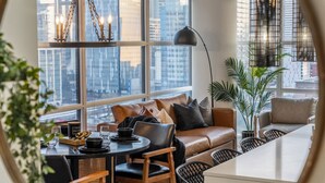 Una sala de estar moderna con un sofá de cuero, una mesa de comedor con sillas y un amplio ventanal con vistas a la ciudad.