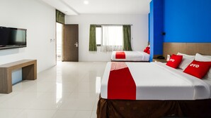 Habitación de hotel con una cama grande, una cama más pequeña, un televisor y un escritorio.