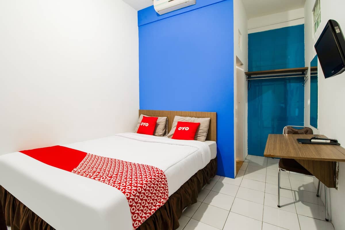 A hotel room with a bed, a desk, and a chair.