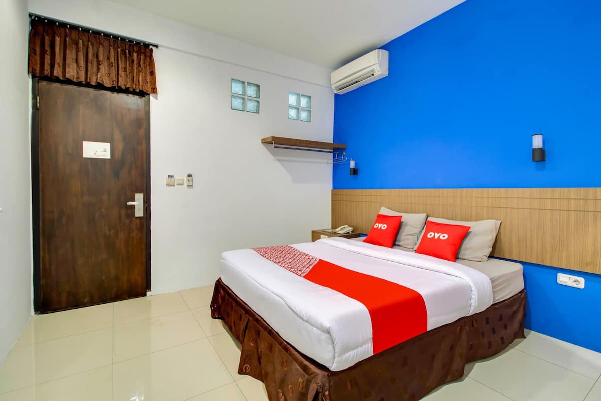 A hotel room with a wooden bed, a blue accent wall, and a wooden headboard.
