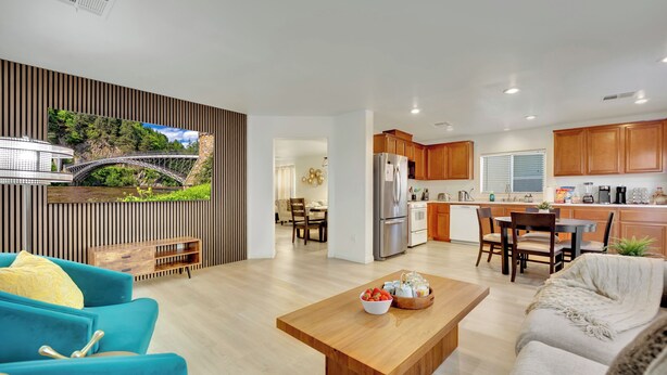 Una sala de estar moderna con una mesa de centro de madera, un sofá azul y un televisor montado en la pared con vistas panorámicas.