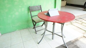 A red table with a laptop on it, a wooden chair, and a green wall. - Hotel O Kost Berkah Near Kebun Teh Wonosari (Malang)