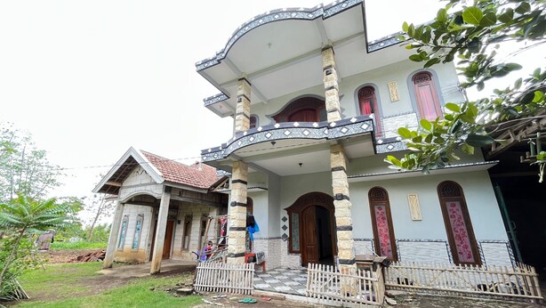 A two-story house with a balcony, a porch, and a gated entrance. - Hotel O Kost Berkah Near Kebun Teh Wonosari (Malang)