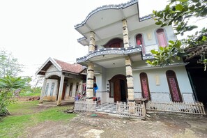 Une maison à deux étages dotée d’un balcon, d’un porche et d’une entrée fermée par un portail.